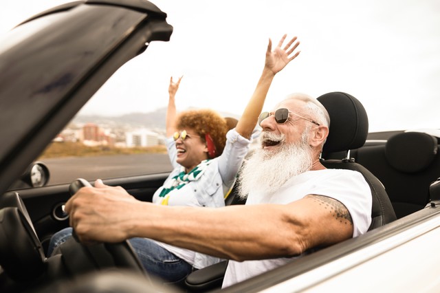 Happy senior couple having fun in convertible car during summer